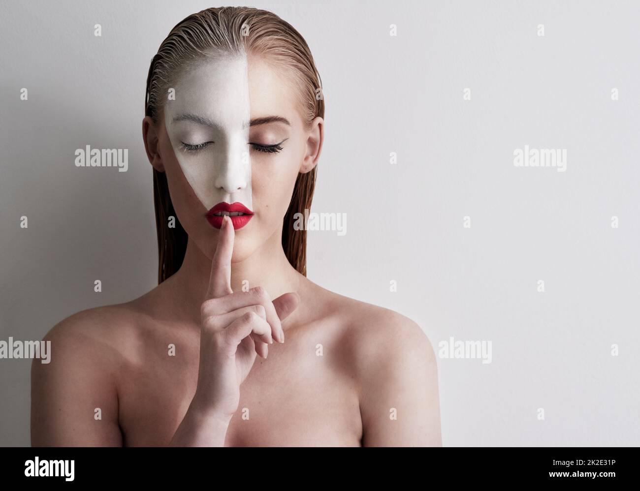 Beauty is art. Shot of a beautiful woman wearing face paint and red lipstick against a plain background. Stock Photo