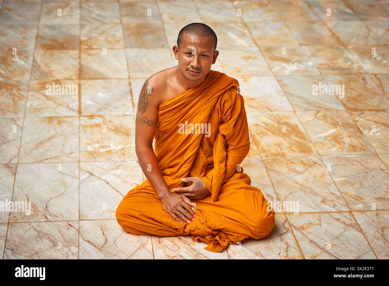 Sitting in quiet meditation. Portrait of a buddhist monk sitting on a monastary floor. Stock Photo