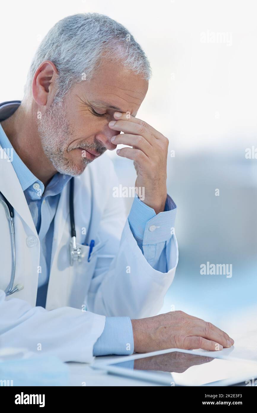 Feeling the strain. Cropped shot of a mature doctor feeling stressed out at work. Stock Photo