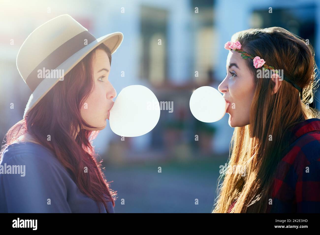 Nothing better than best friend being silly together. Shot of two young friends blowing chewing gum while facing each other. Stock Photo