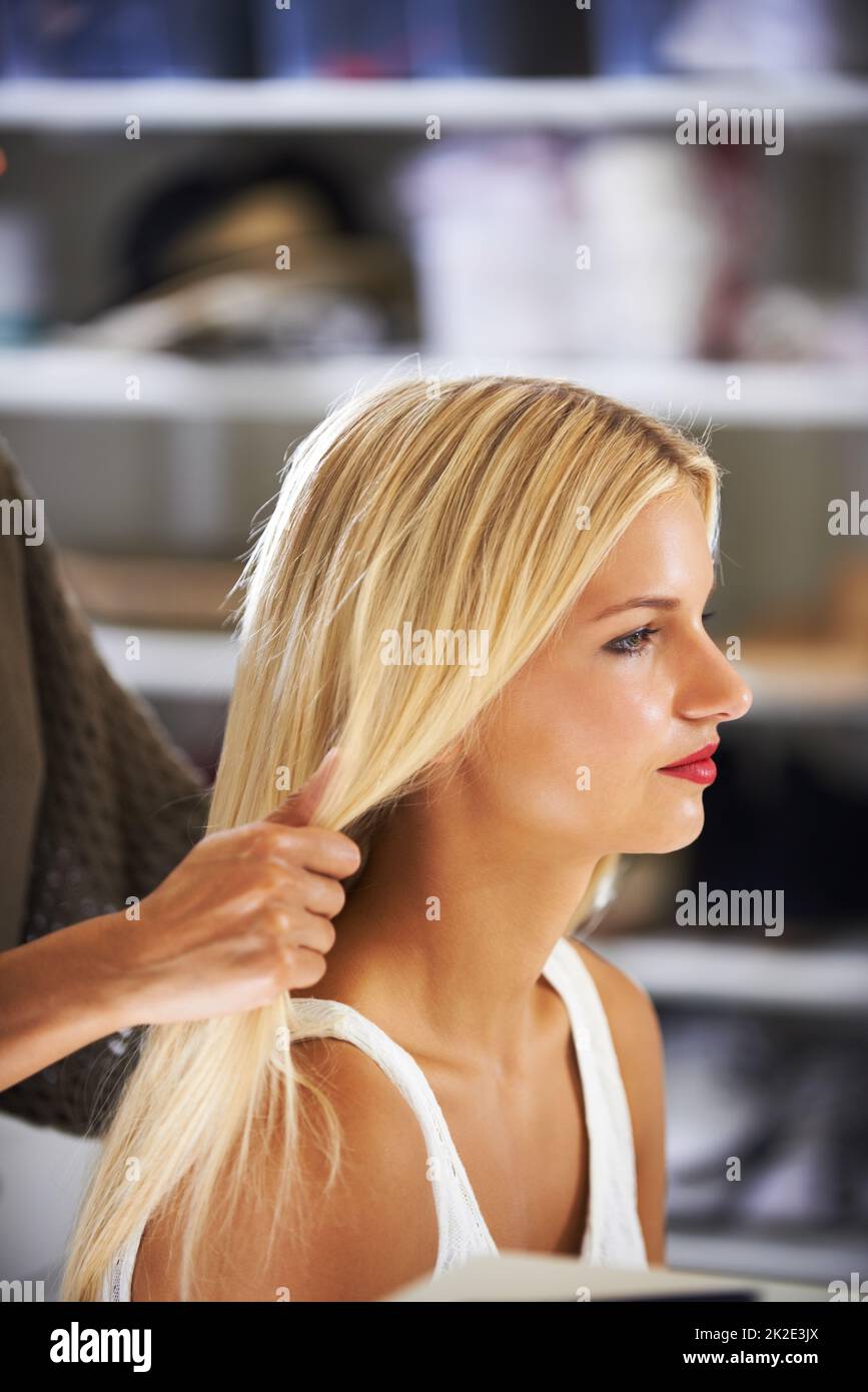 Behind the scenes prep. Pretty young woman having her hair done by a stylist. Stock Photo