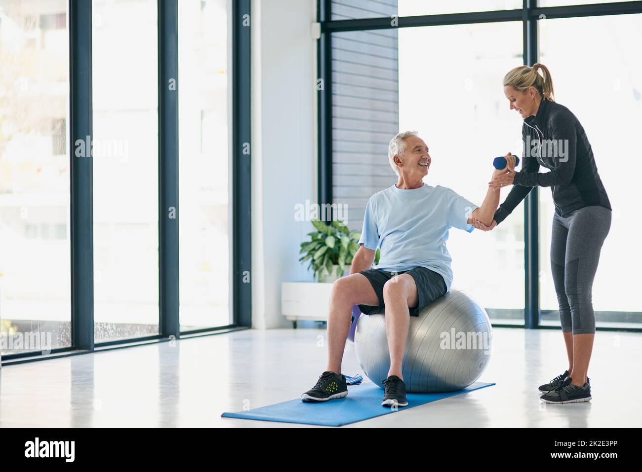 Lets lift this up a little higher. Full length shot of a friendly female physiotherapist helping her senior patient work out with weights. Stock Photo