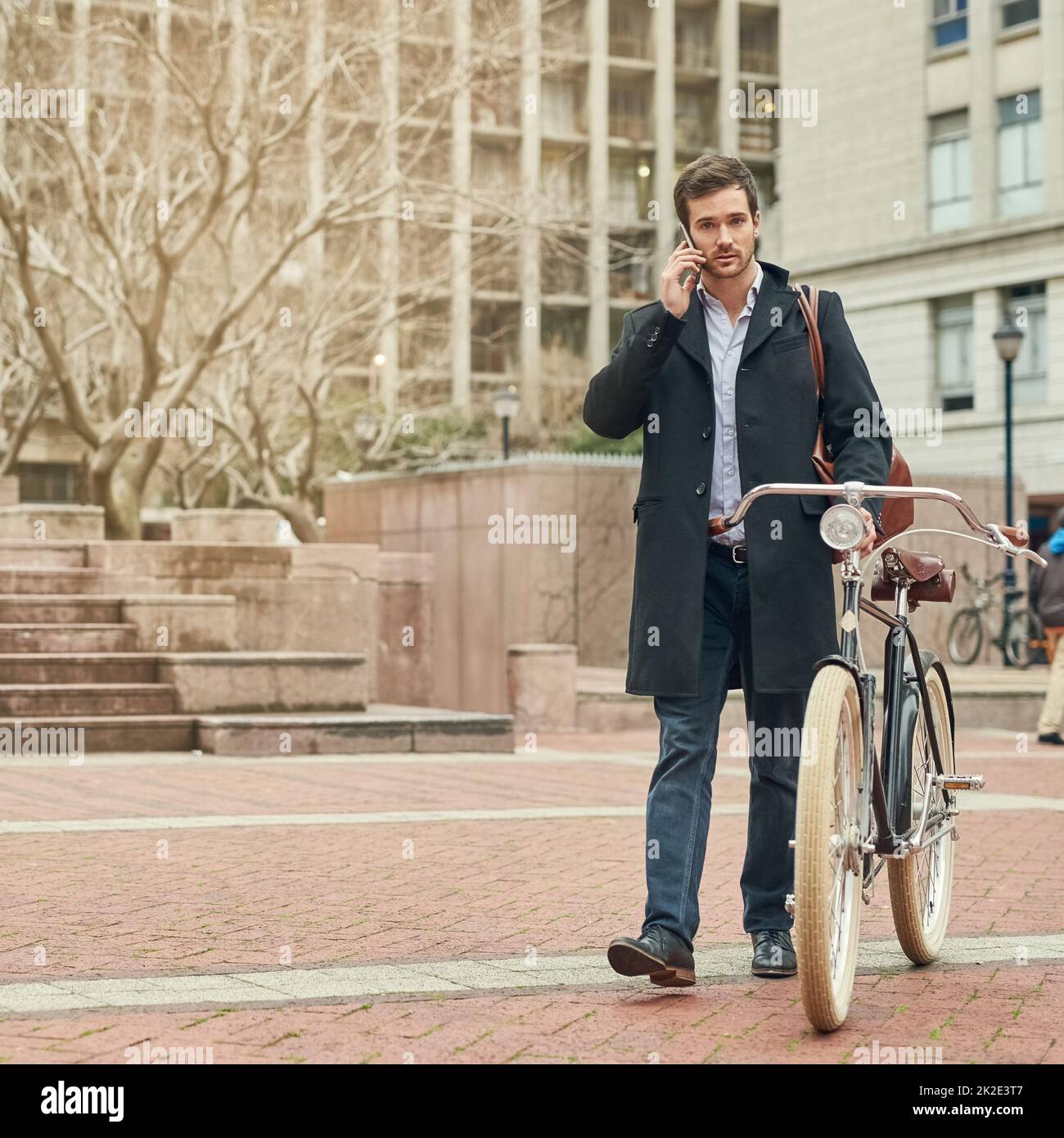 En route to work through the city. Portrait of a young businessman commuting to work with his bicycle. Stock Photo