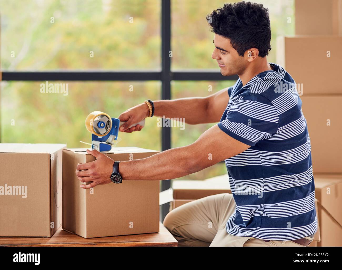 Packing up the last box. Shot of a young man taping up boxes on moving day. Stock Photo