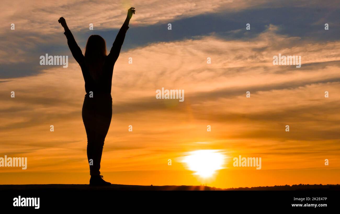 Woman silhouette with arms raised. Stock Photo