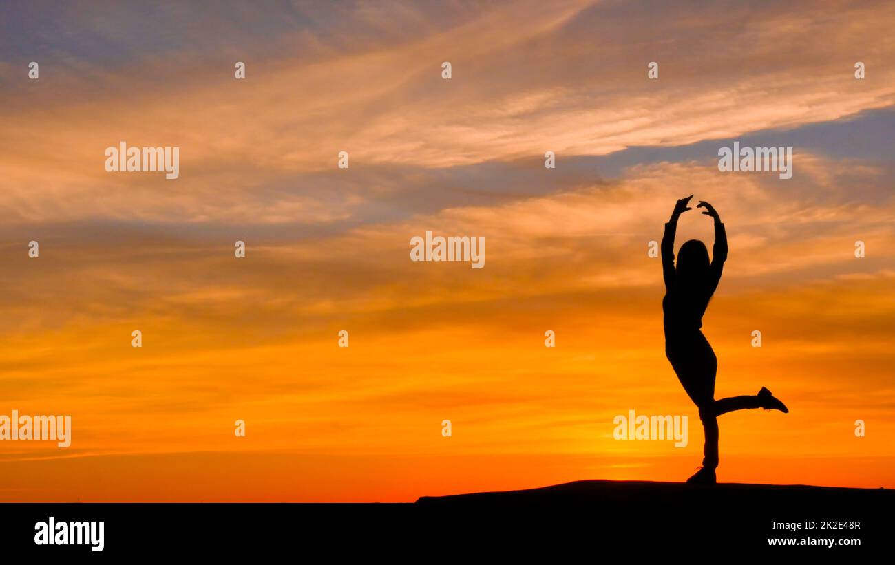 Silhouette of woman with arms raised in a ballerina position. Stock Photo