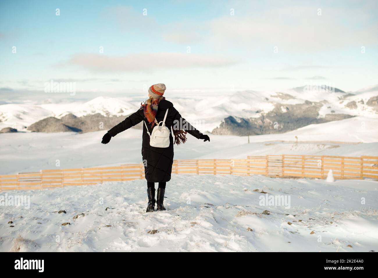 Woman with colorful scarf and hat enjoying sunny winter day, clear blue sky. Stock Photo