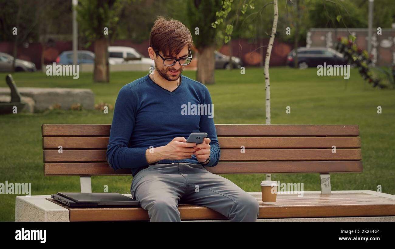 Portrait focused man writing using mobile phone outdoor. Stock Photo