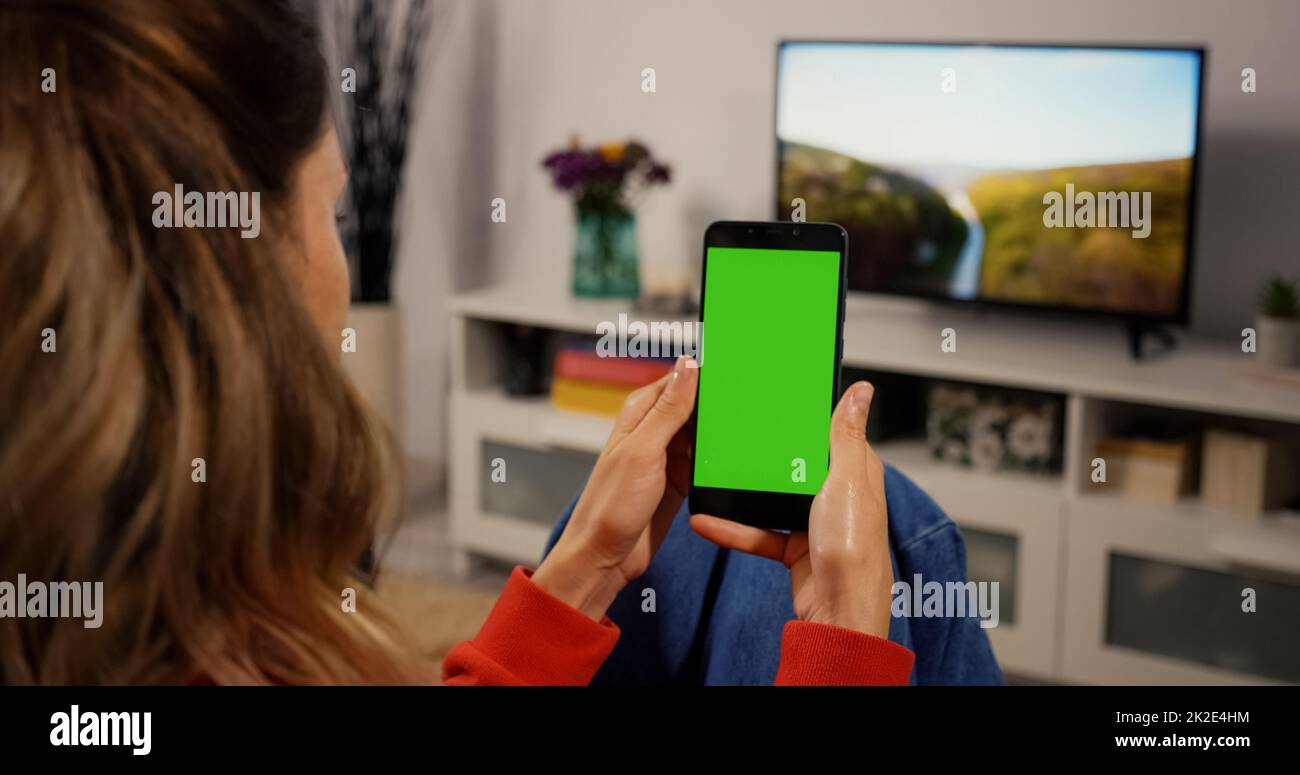 Woman Using Smartphone with Green Screen for Copy Space Close up Chroma Key Mockup. Scrolling Gestures. Girl watcing gadget green screen and touch dis Stock Photo