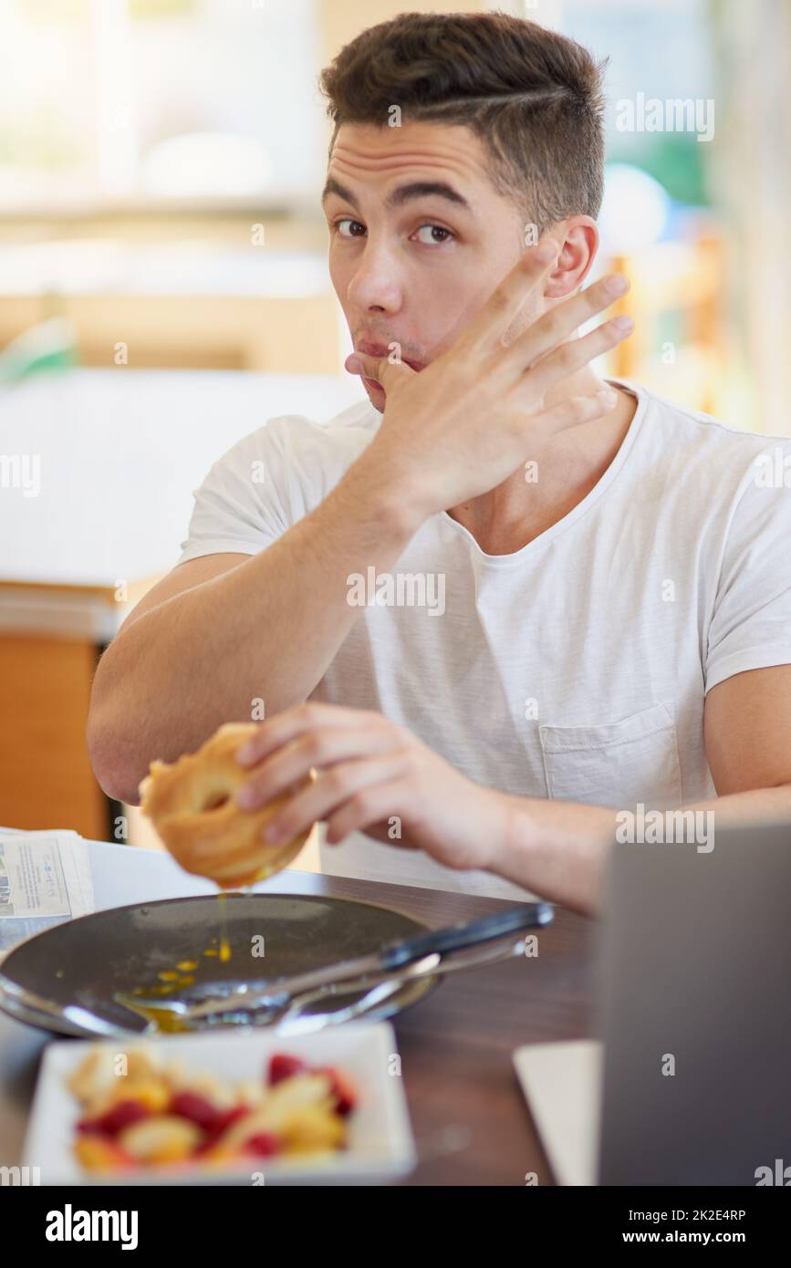 Its finger licking good. Cropped shot of a bachelor enjoying breakfast at home. Stock Photo