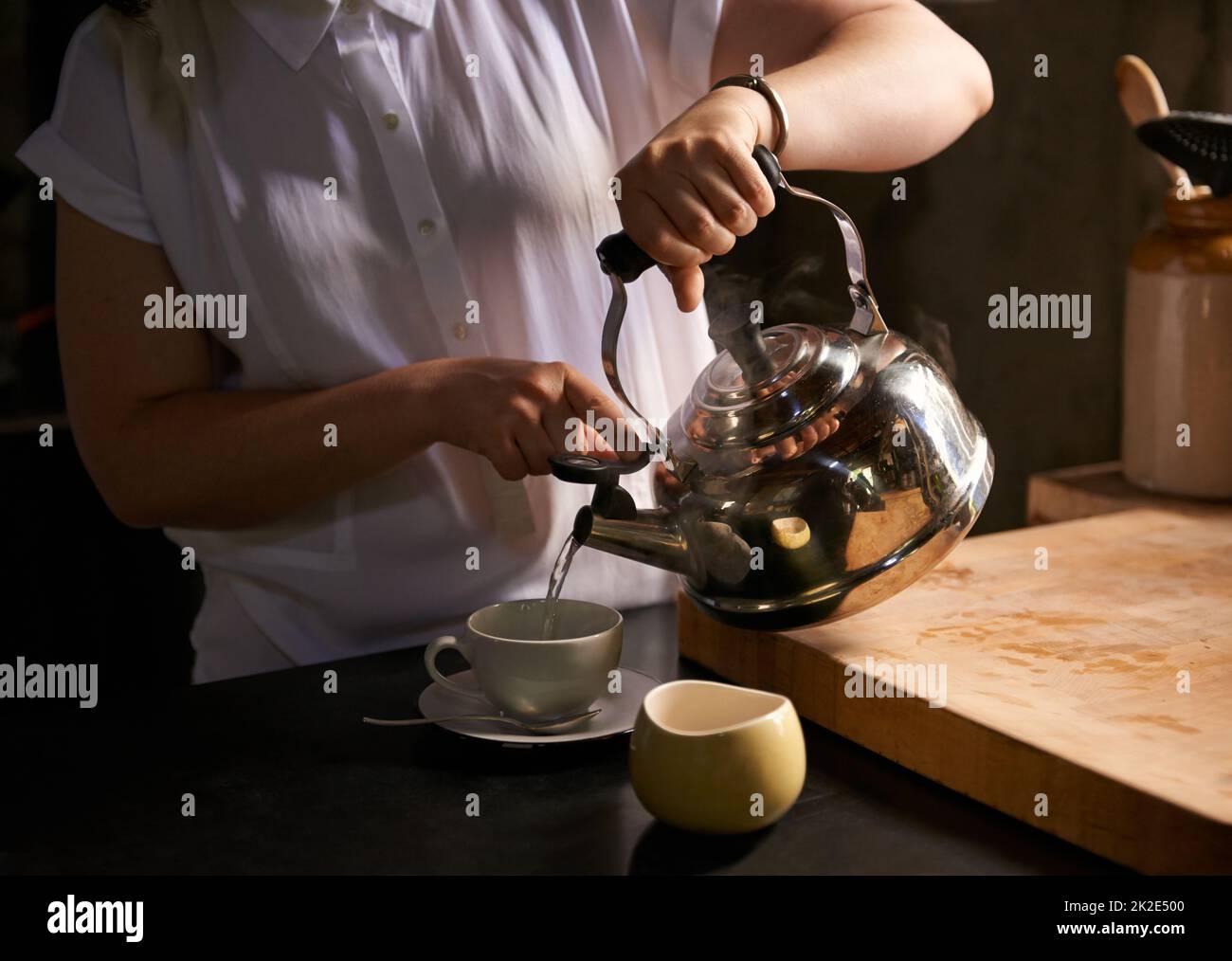 Brewing the perfect cup. Cropped shot of a young woman making a cup of tea in her kitchen. Stock Photo