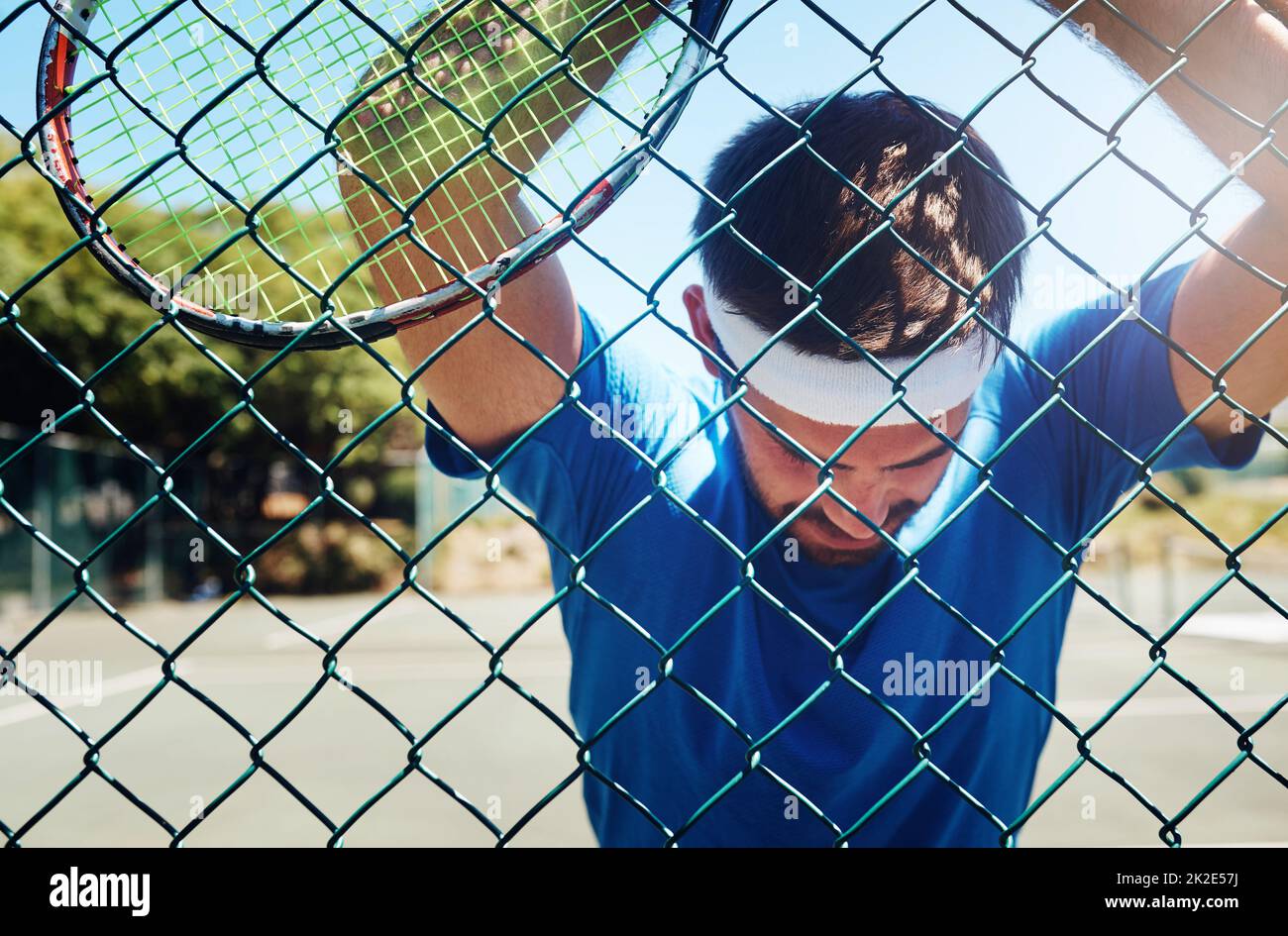 I need to catch my breath. Cropped shot of a handsome young sportsman taking a moment to breathe during tennis practise. Stock Photo