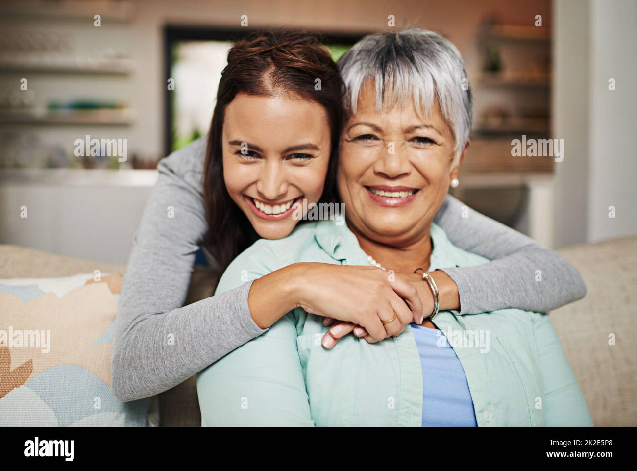 All grown up, but still her mothers daughter. Cropped portrat of a young woman hugging her mature mother in the living room. Stock Photo