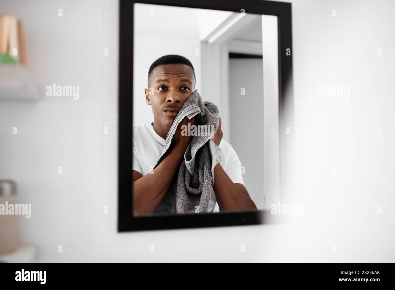 A fresh face is how you start your day. Cropped shot of a man looking into the mirror while drying his face with a towel. Stock Photo
