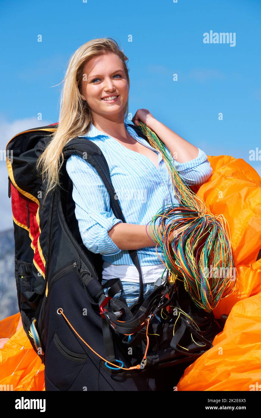 Its a great day to fly. Shot of a young woman getting ready to go paragliding. Stock Photo