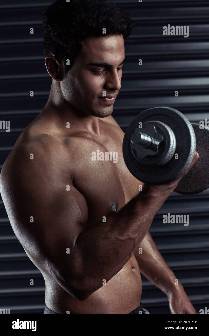 Building big and bulging biceps. Cropped shot of an athletic young man working out with a dumbbell. Stock Photo