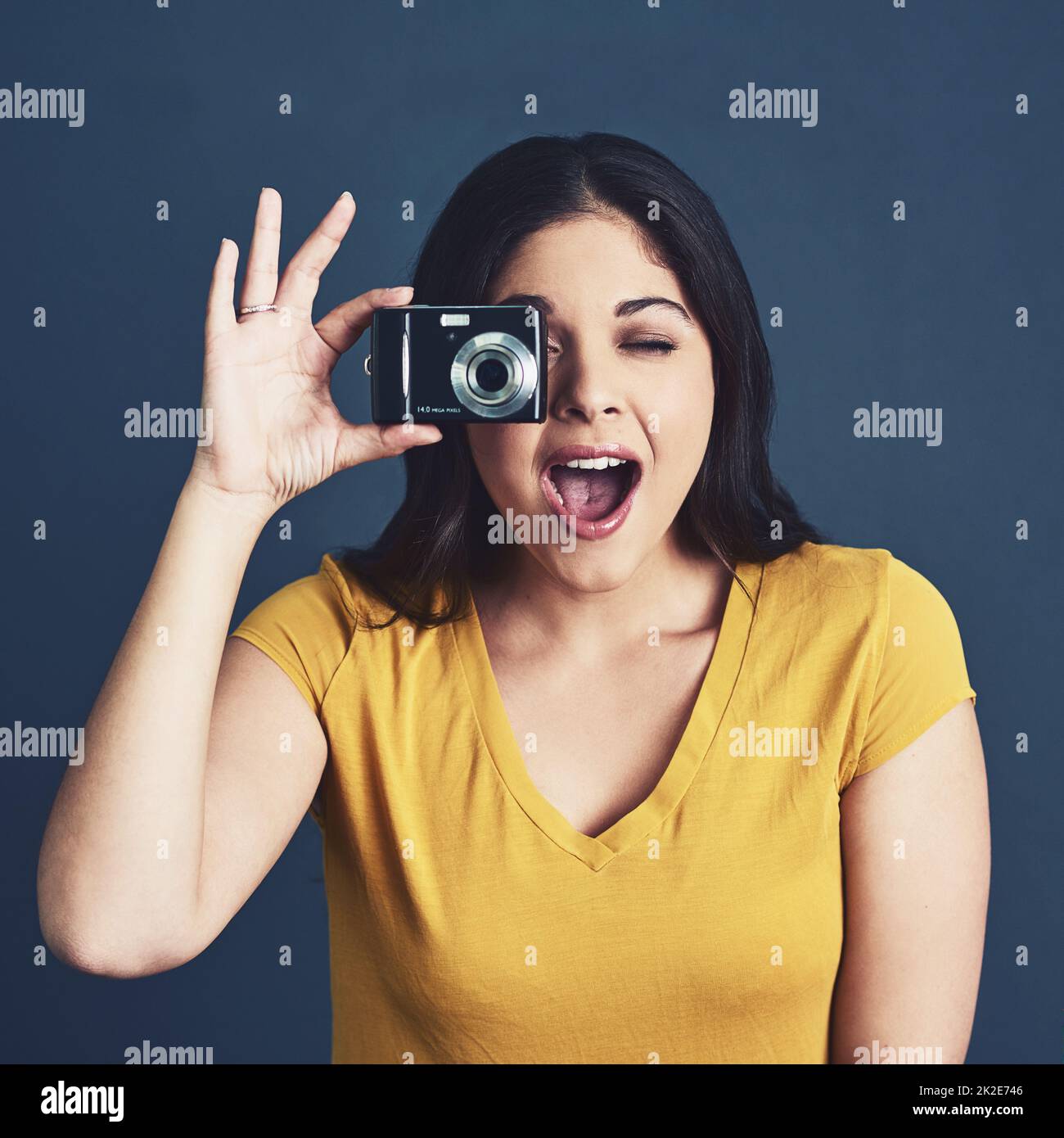 Youre so photogenic. Studio portrait of an attractive young woman taking a photo against a blue background. Stock Photo