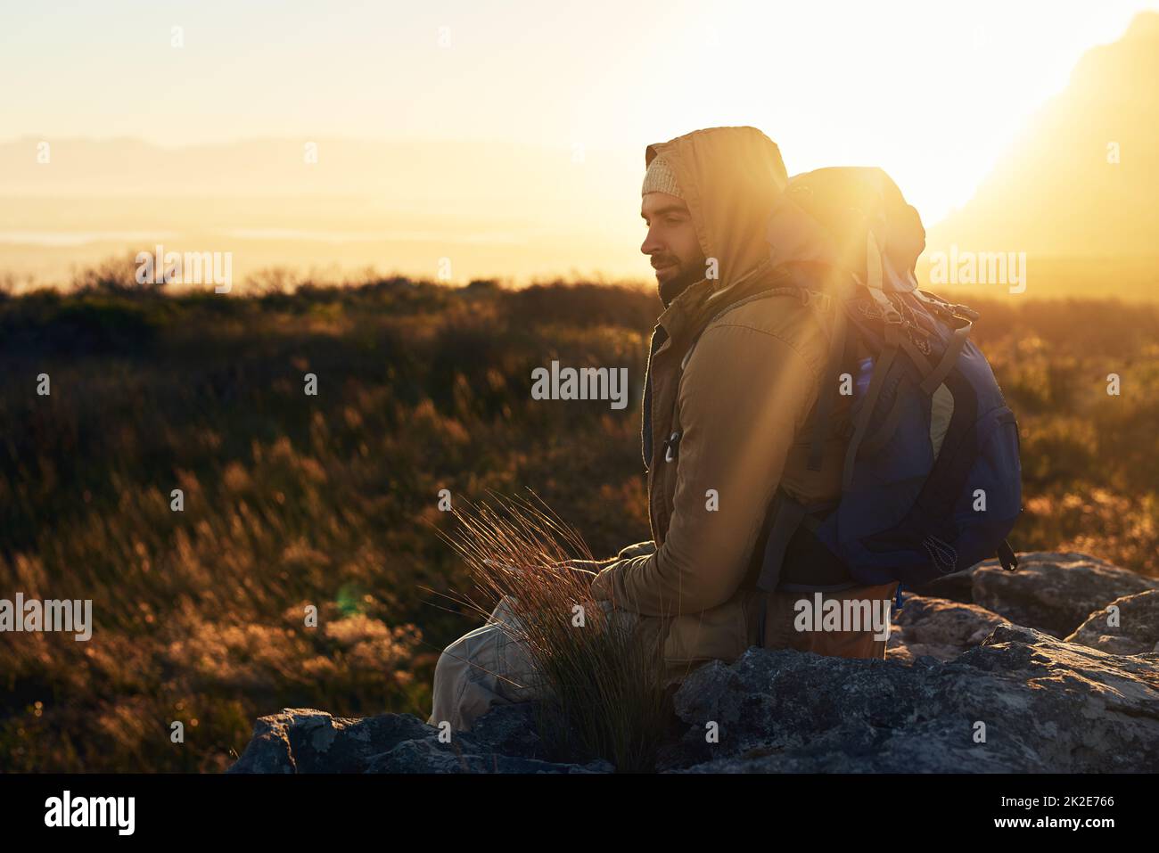 The best spot to ponder over the yonder. Shot of a hiker siting on top of a mountain in deep thought. Stock Photo