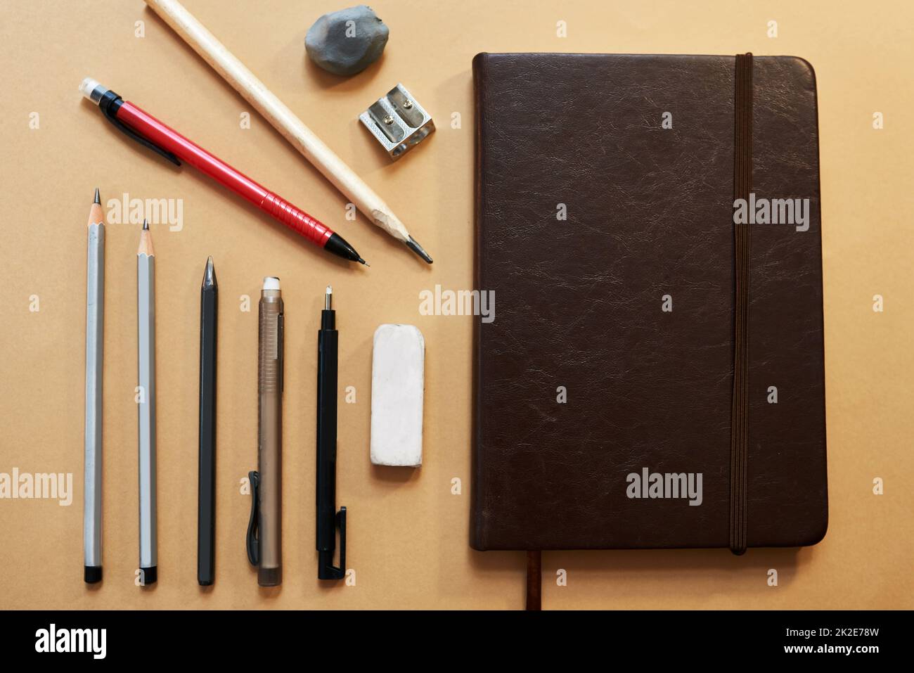 Give your inner artist room to play. Studio shot of a sketchpad and other various artistic against a brown background. Stock Photo