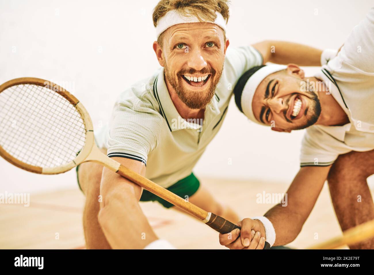 Hit the ball off the wall. Shot of two young men playing a game of squash. Stock Photo