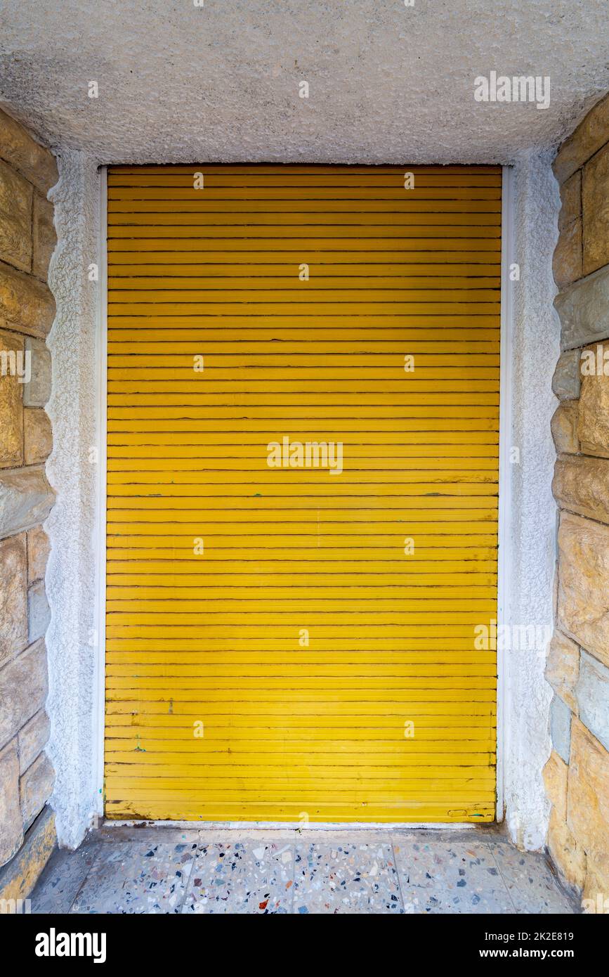 Bricks stone wall and closed yellow roll-up door Stock Photo
