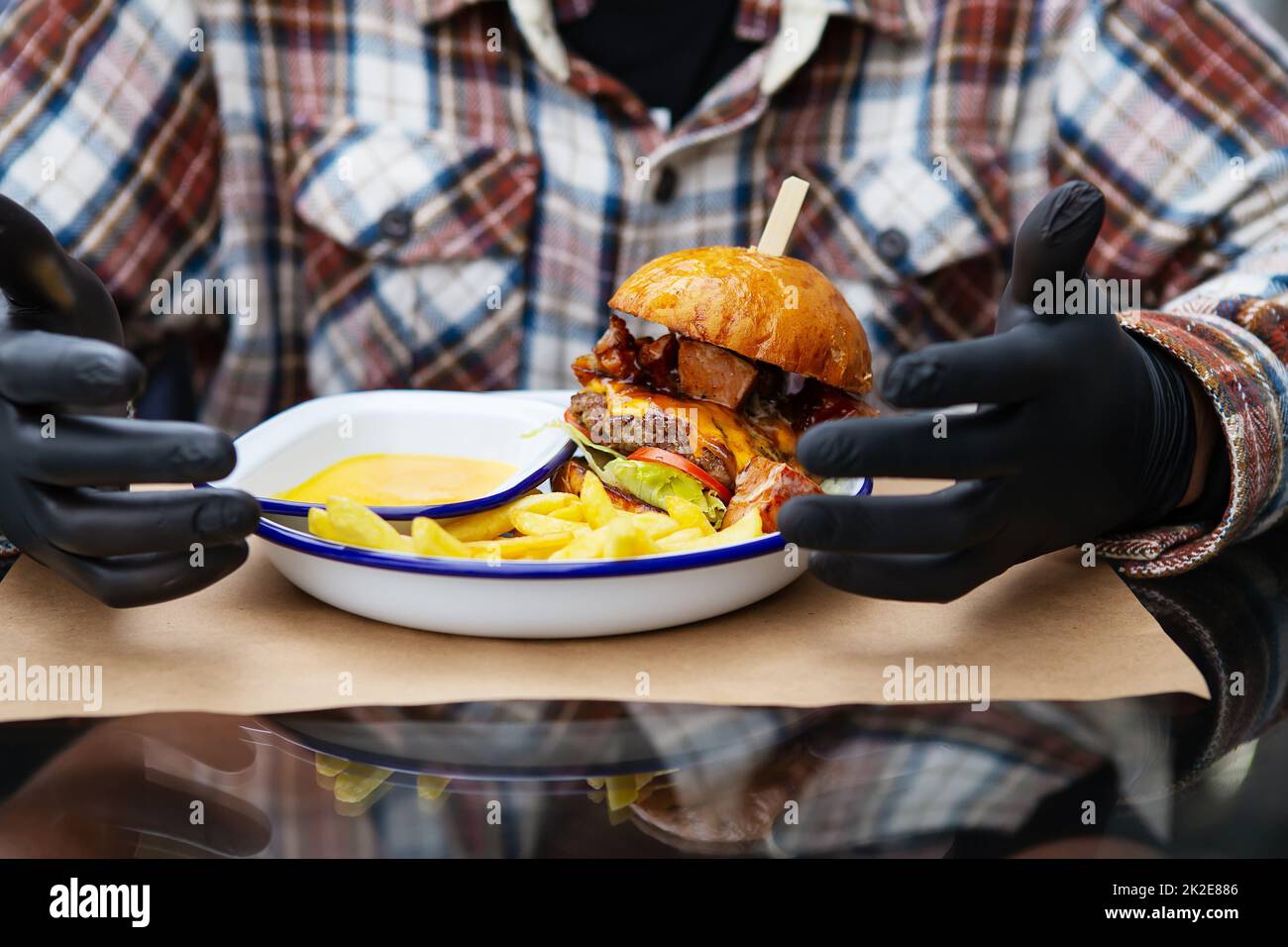 The concept of fast food and takeaway food. A man in black latex gloves
