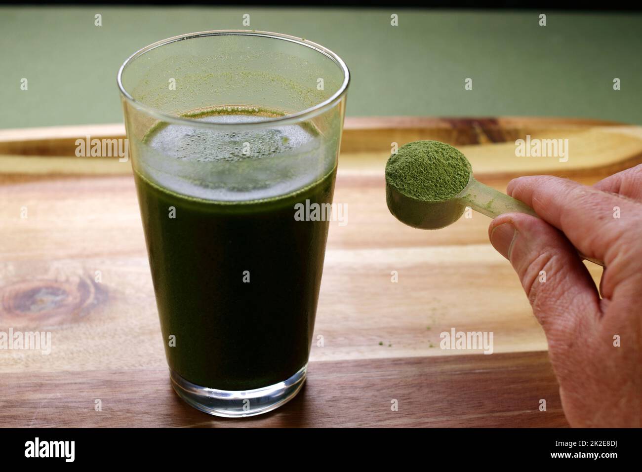 Hand Showing a Scoop of Organic Celery Powder Near Beverage Stock Photo