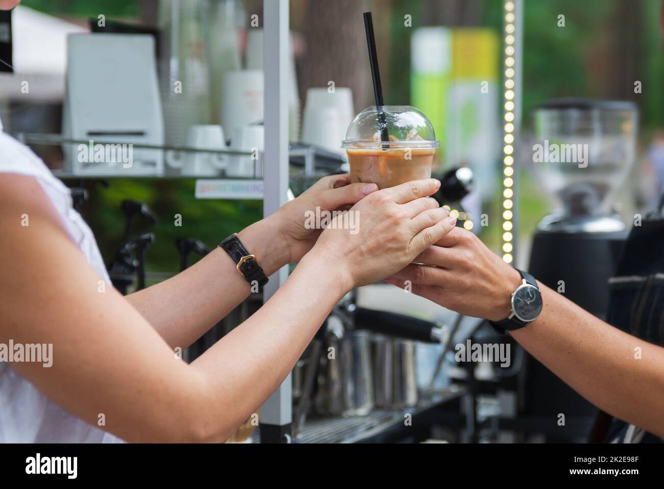 Seller giving to the customer a plastic glass with the iced latte Stock Photo