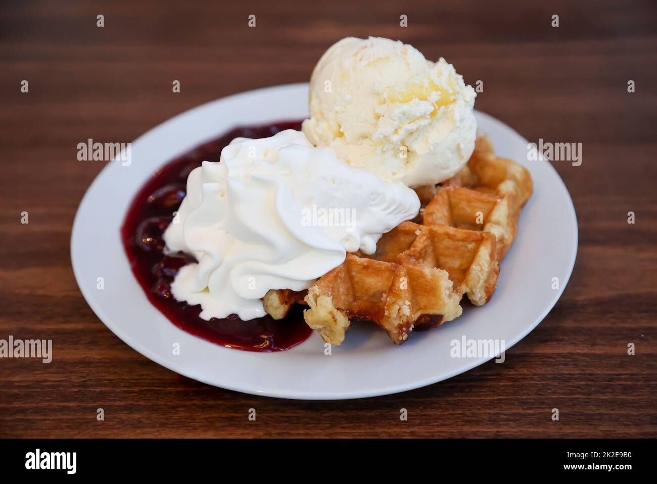 A hot waffle with cherries, ice cream and whipped cream Stock Photo - Alamy
