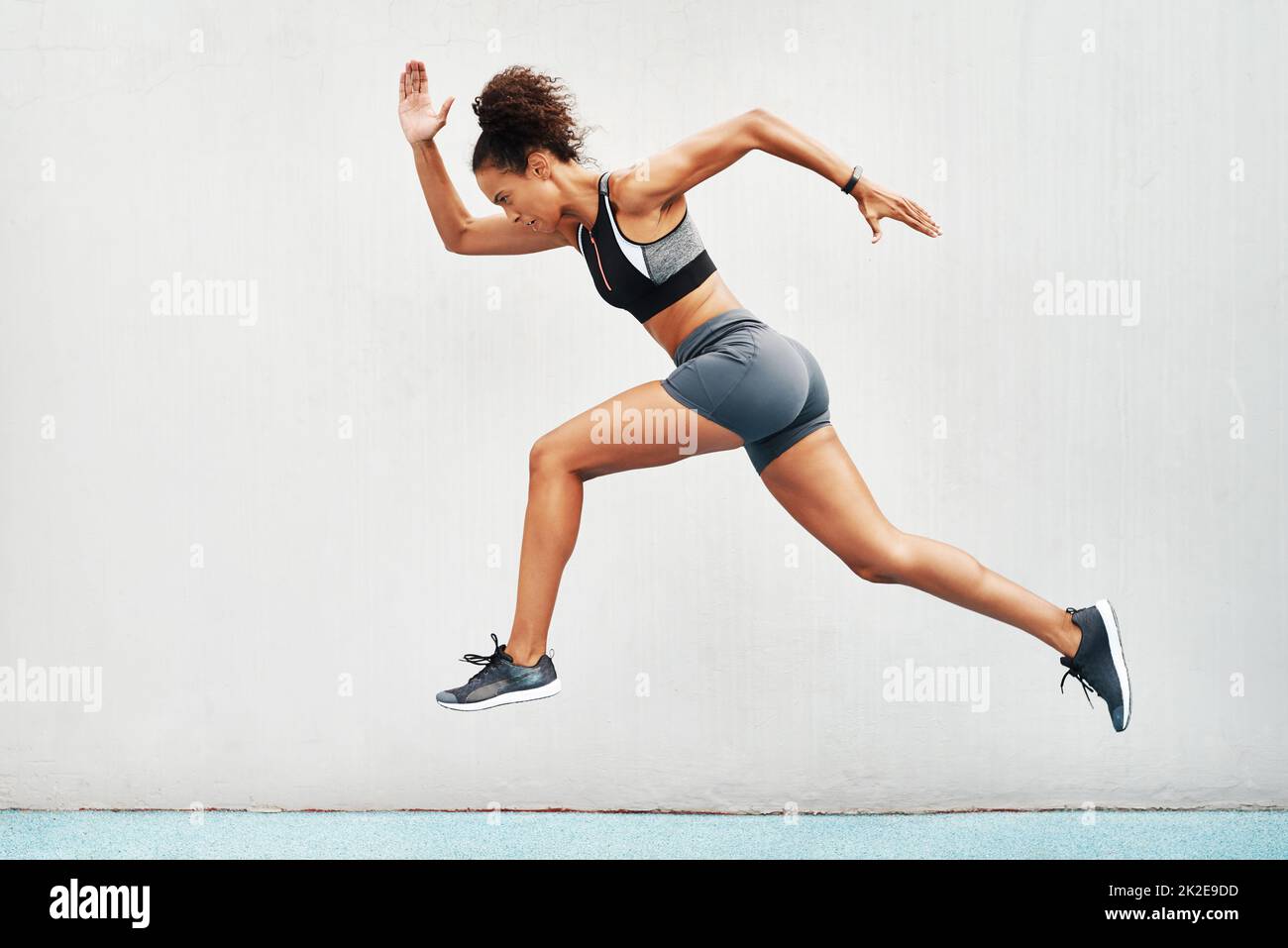 As we run, we become. Full length shot of an attractive young athlete jumping while on a track field during an outdoor workout session. Stock Photo