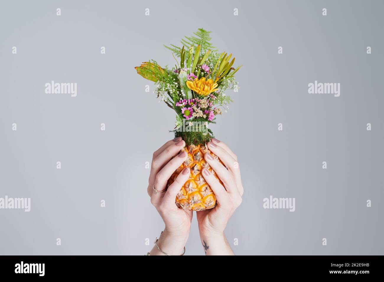 For the love of all things beautiful and natural. Shot of an unrecognizable woman holding a pineapple stuffed with flowers. Stock Photo