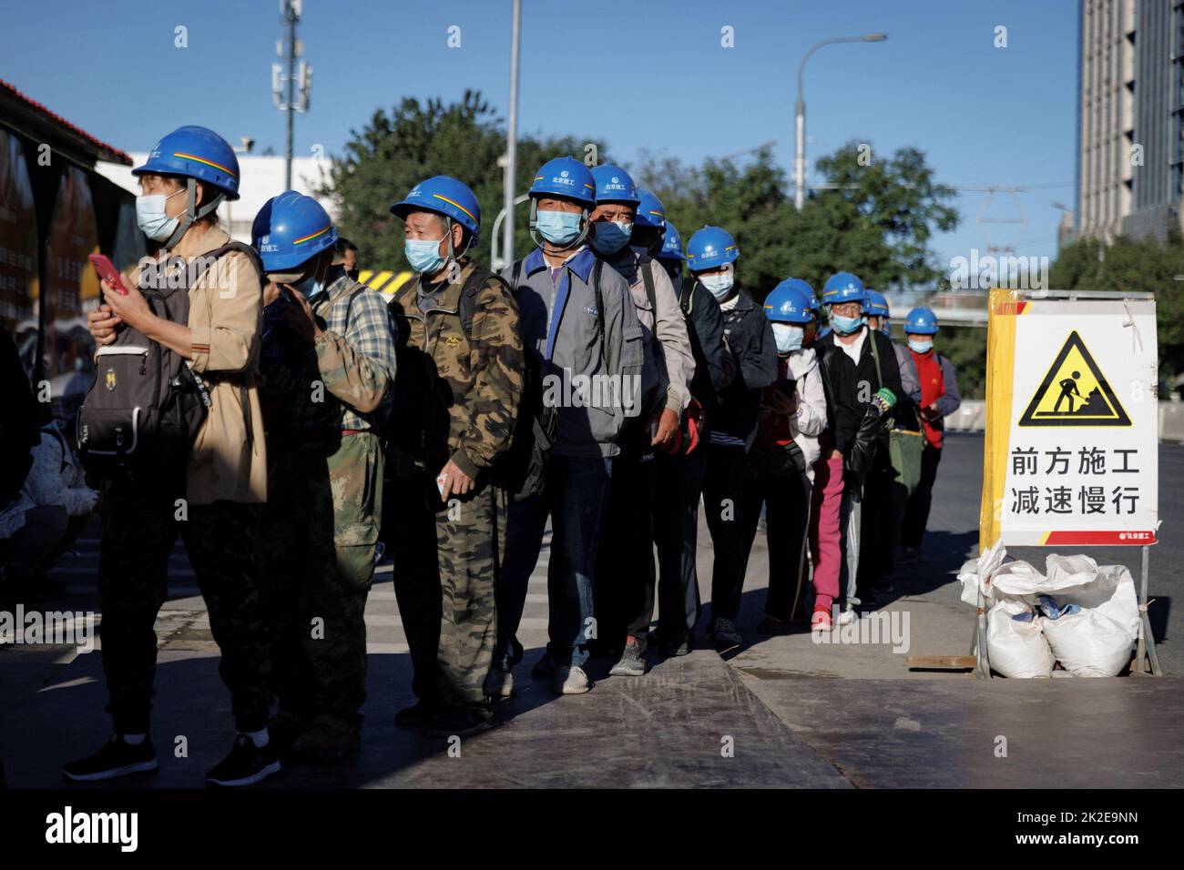 Workers line up to enter the construction site of the new Workers' Stadium in Beijing, China, September 23, 2022. REUTERS/Thomas Peter Stock Photo