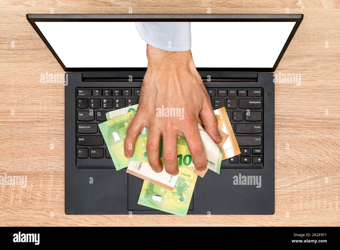 Hand reaching out of laptop screen to steal money Stock Photo