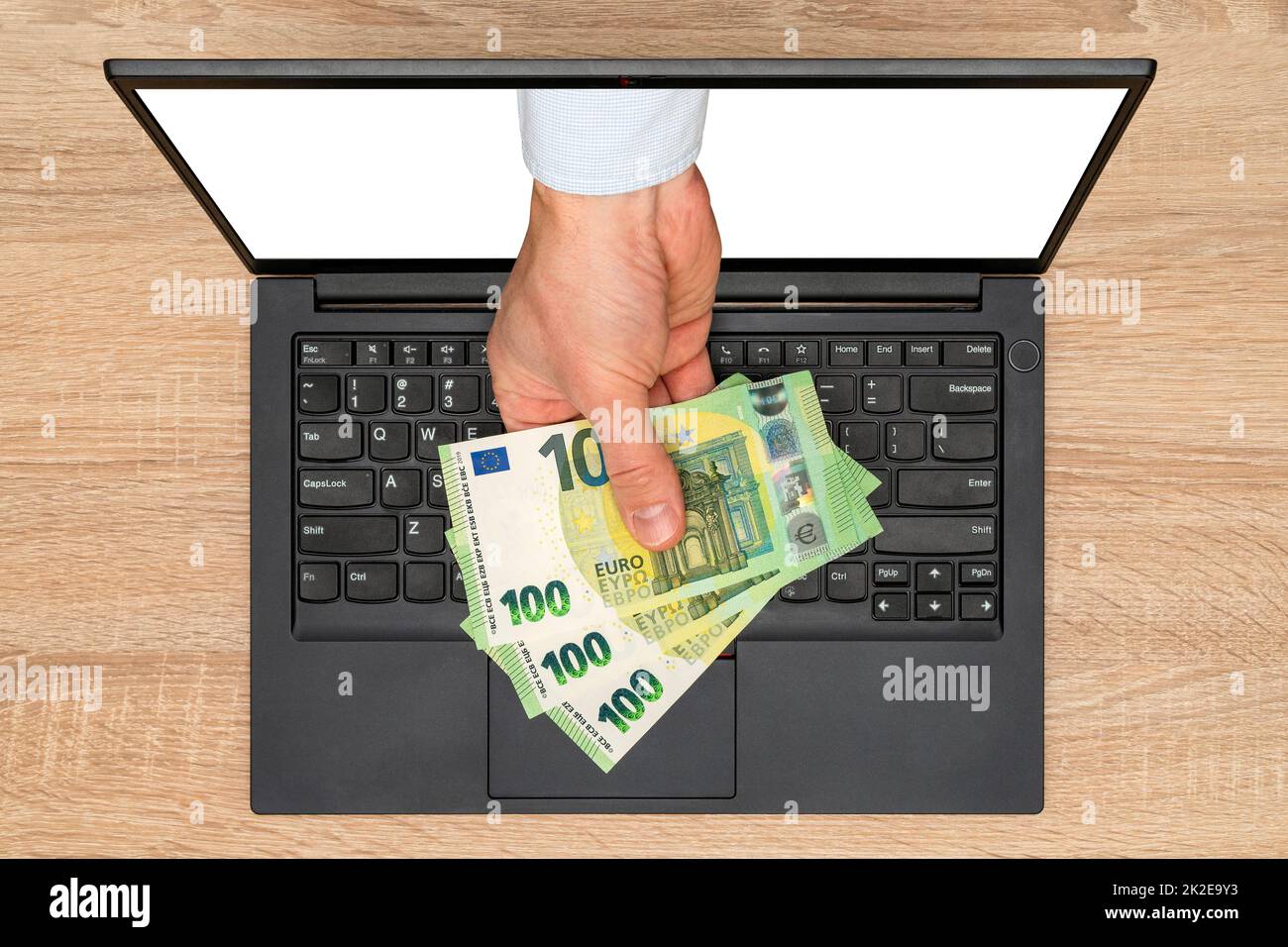 Hand giving money through a laptop screen Stock Photo