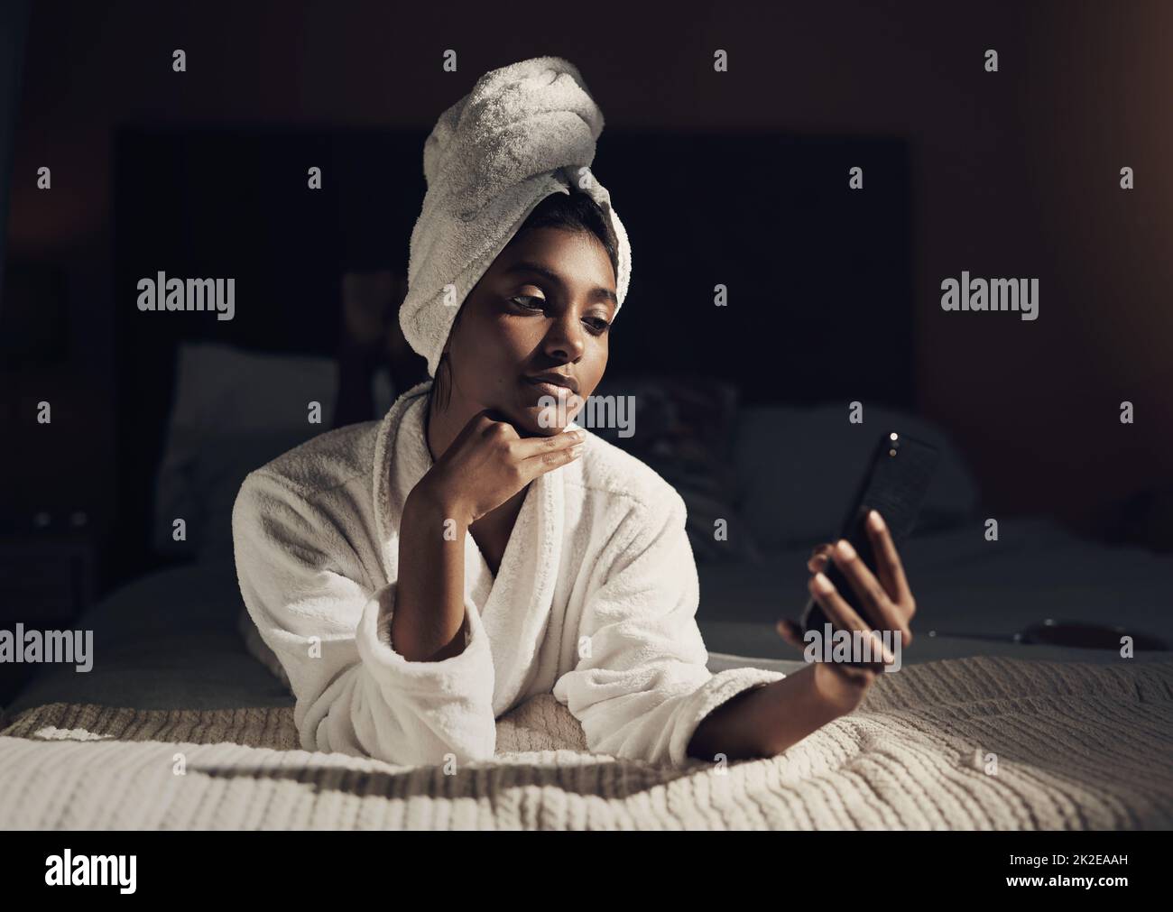 Nothing says you matter like making time for yourself. Shot of a young woman using a smartphone while going through her beauty routine at home. Stock Photo
