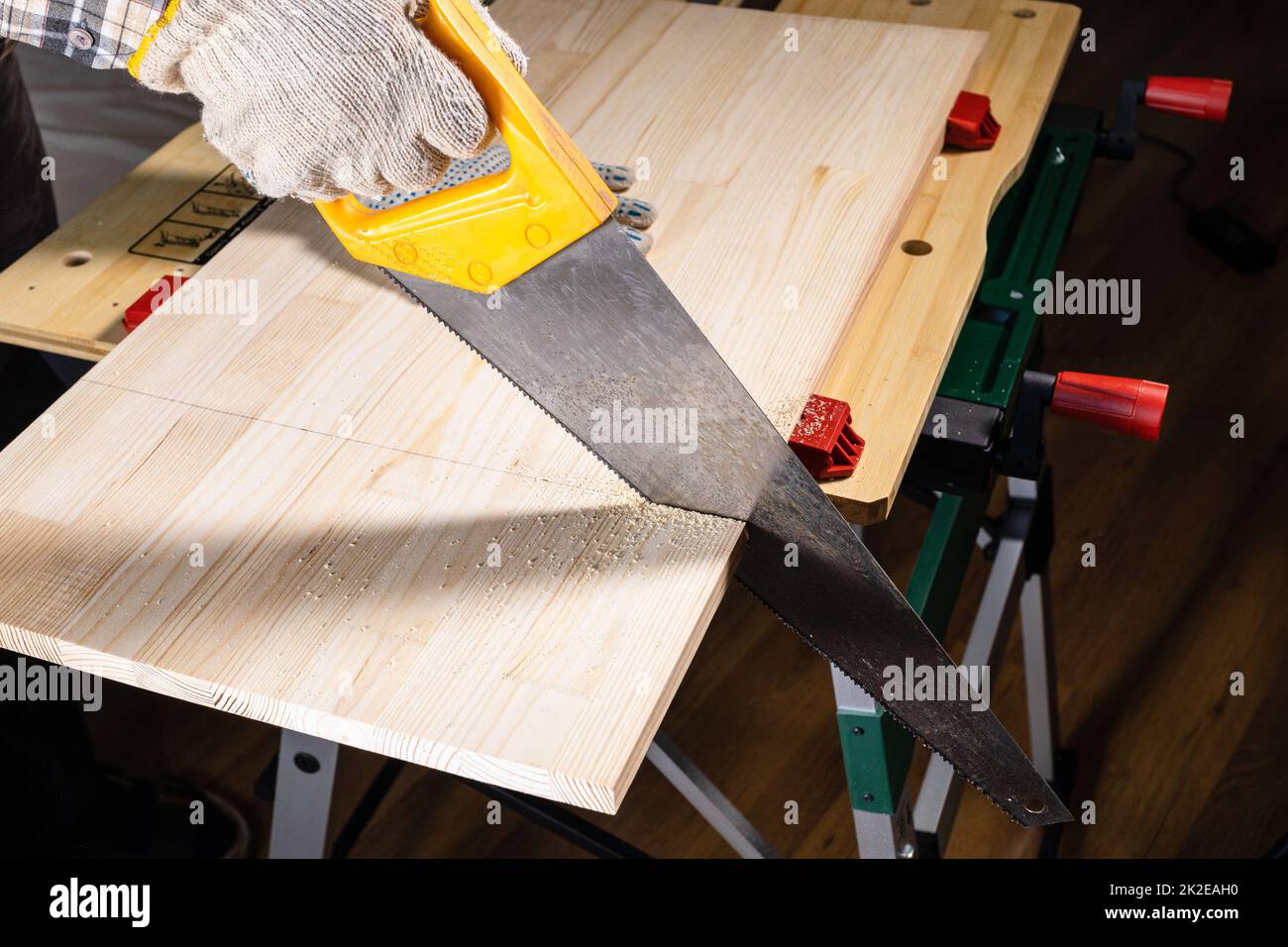 woodworker saws wooden board with hand saw Stock Photo