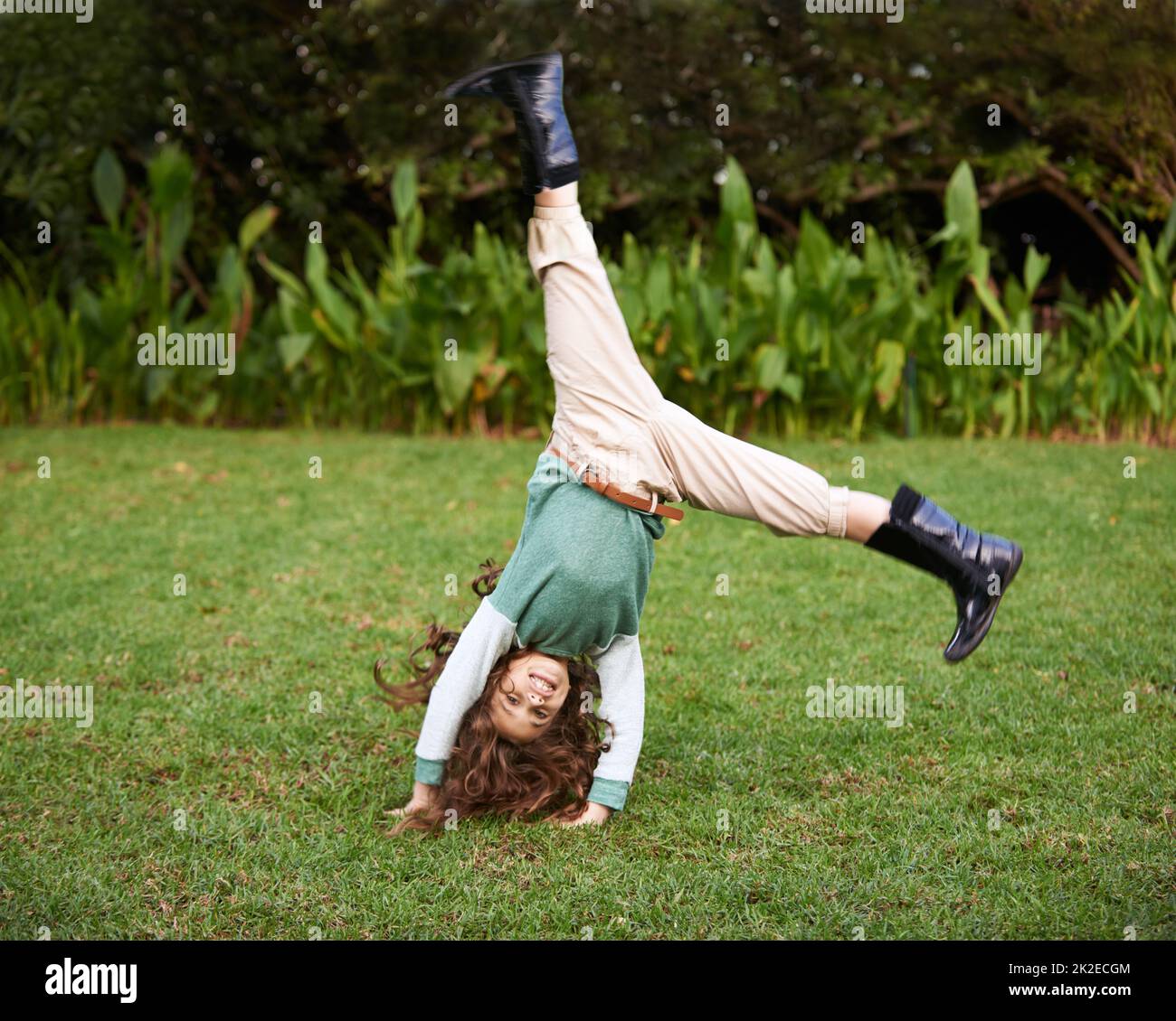 Doing cartwheels is so much fun. Shot of a cute little girl doing cartwheels on the grass. Stock Photo