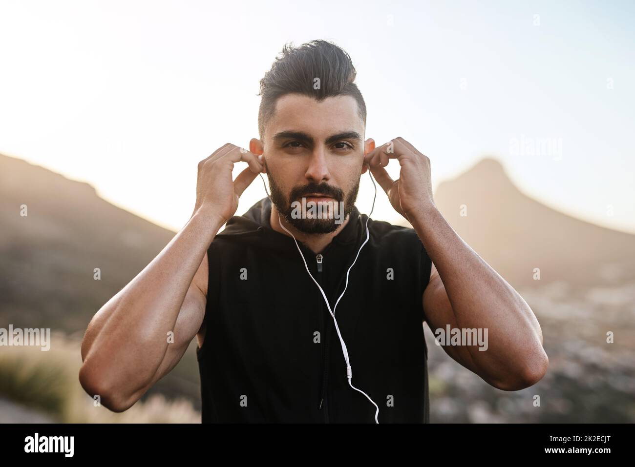 I cant workout without some of my favourite tunes. Portrait of a young man listening to music while exercising outdoors. Stock Photo