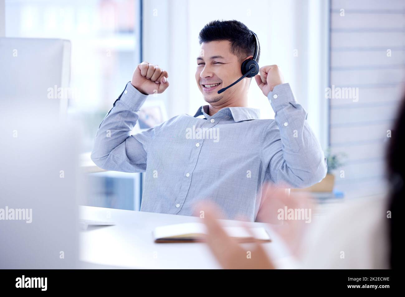 Another big sale made by me. Shot of a young call centre agent cheering while working on a computer in an office. Stock Photo