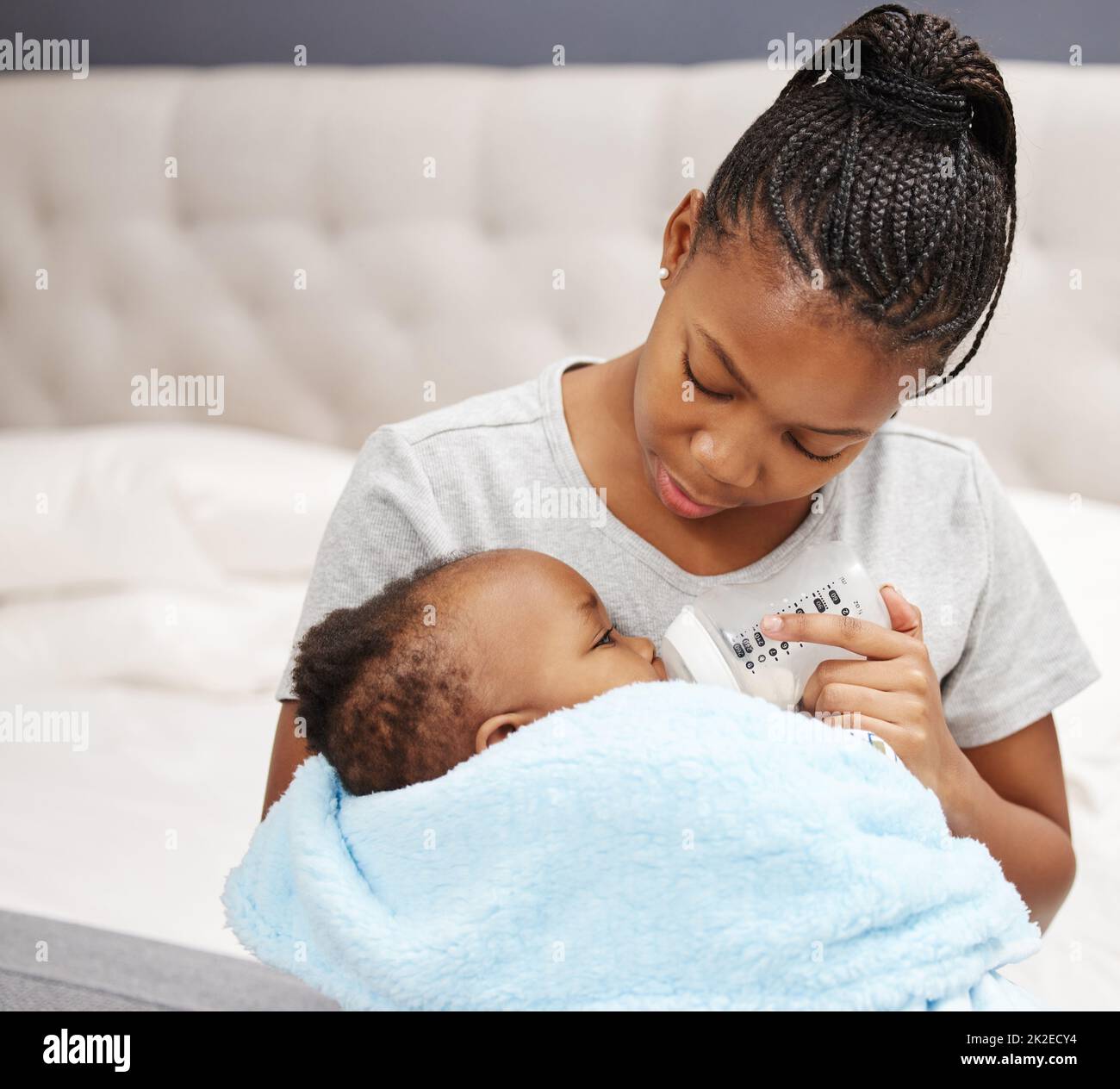 Eat. Sleep. Love. Shot of a woman bottle feeding her baby at home Stock