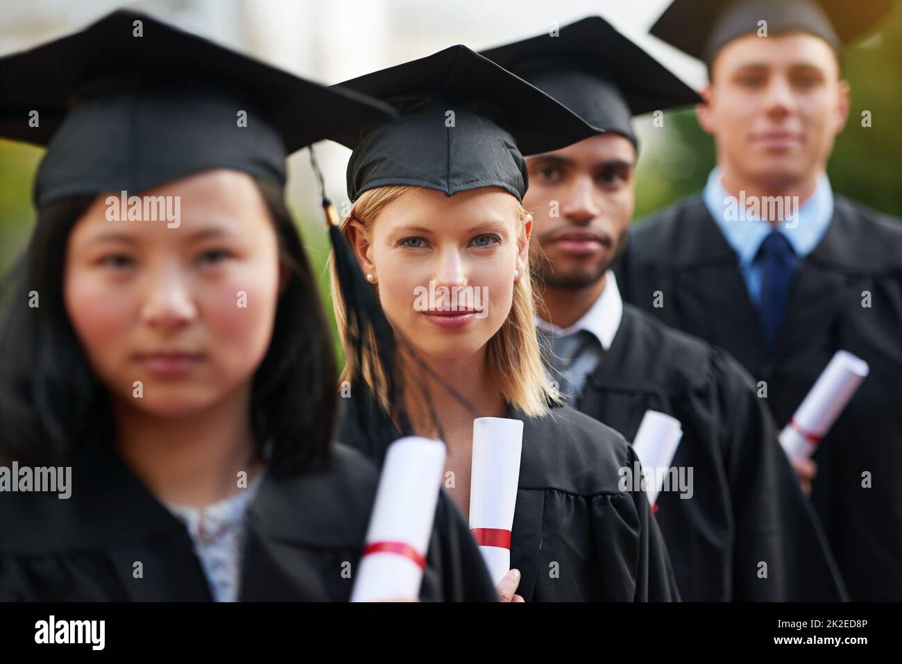 This is the beginning, of anything you want. A group of college graduates standing in cap and gown and holding their diplomas. Stock Photo