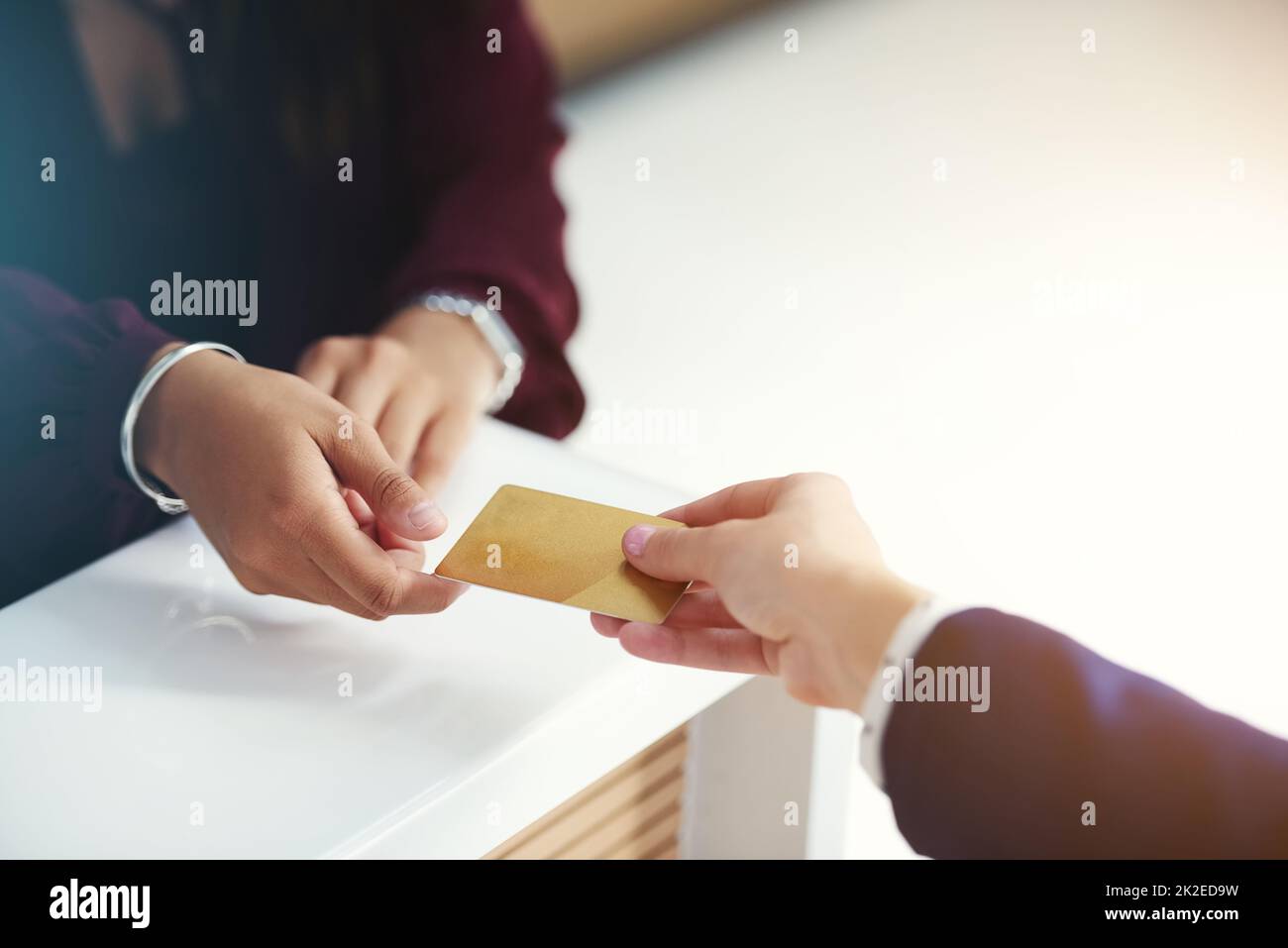 Put it on my card. Cropped shot of an unrecognisable person handing over a credit card for payment. Stock Photo