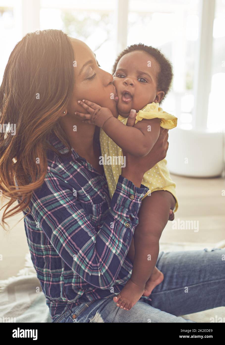 Showering her with kisses. Cropped shot of a young mother and her little baby girl at home. Stock Photo