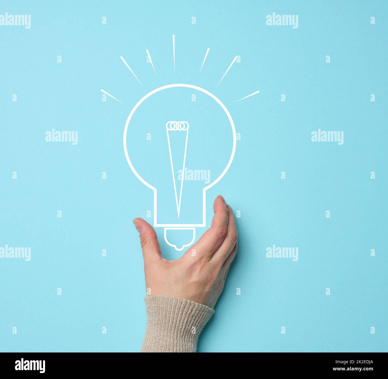 Woman's hand and a drawn electric lamp on a blue background. The concept of searching for ideas and solutions, brainstorming. Switching to alternative forms of energy Stock Photo