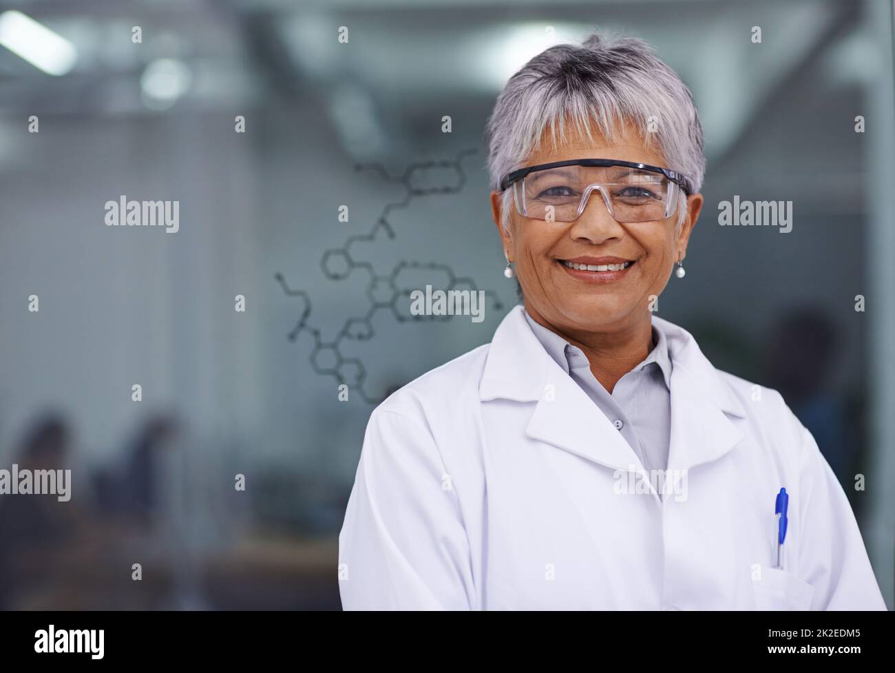 Her discovery will change lives. A female scientist standing before a glass board with a formula