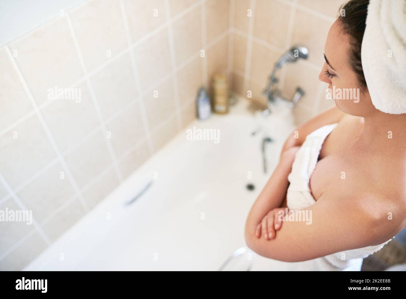 Always thinking of ways to save water. High angle shot of a beautiful young woman getting ready to take a bath at home. Stock Photo