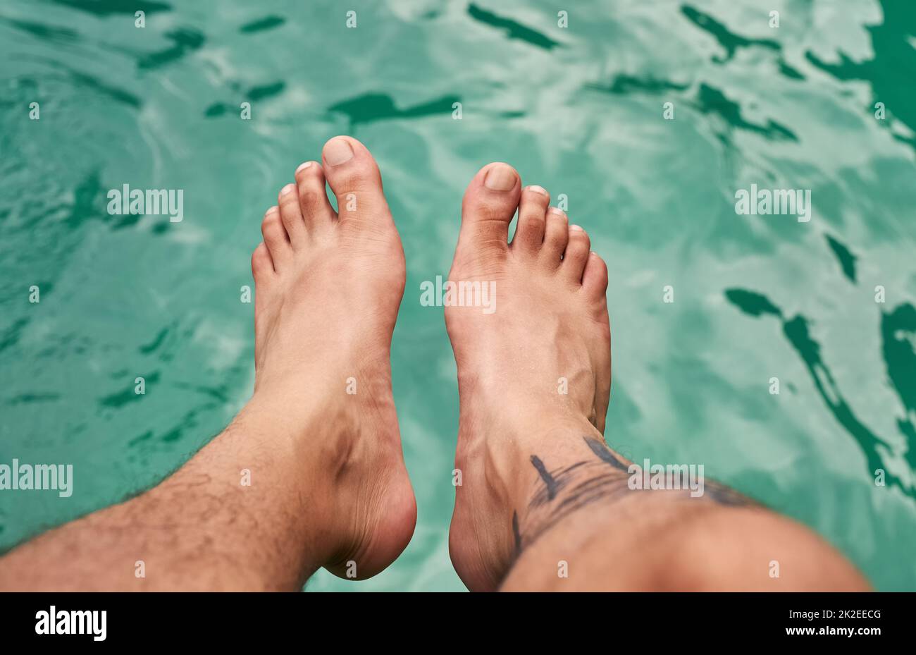 Getting a feel for the water. High angle shot of a mans feet above the water. Stock Photo