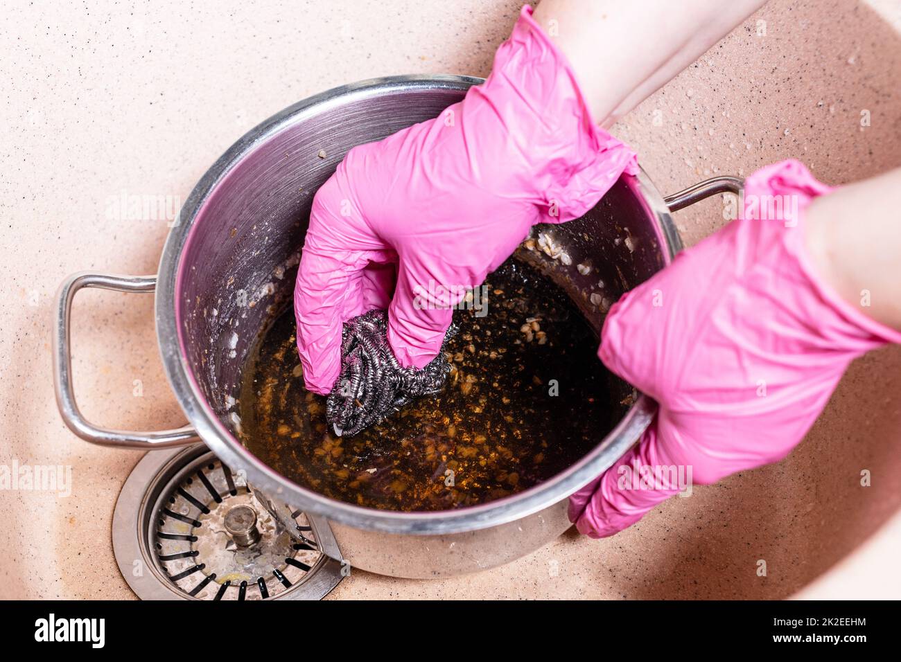 hands scrub stewpan with burnt food by sponge Stock Photo