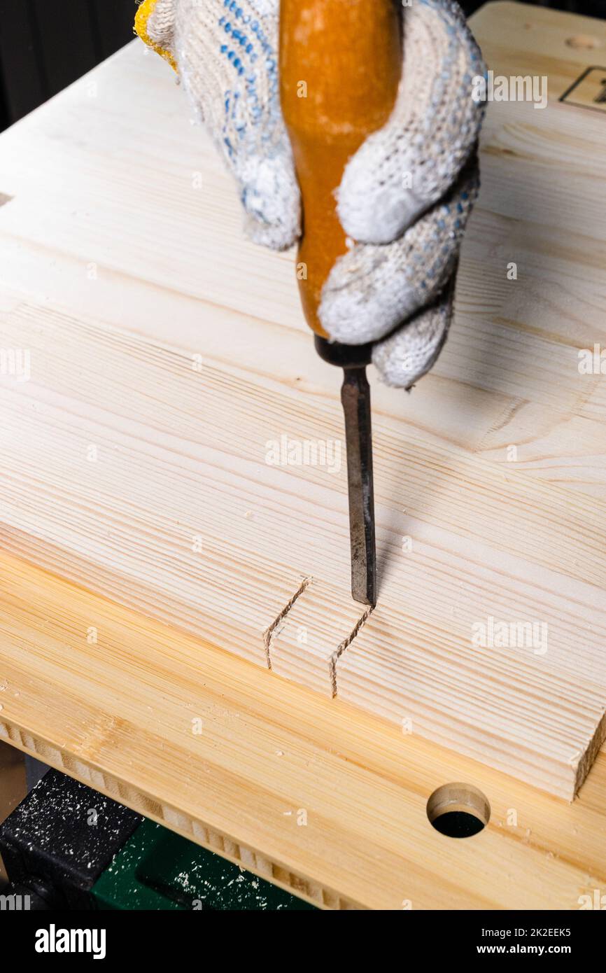 carpenter using chisel cuts groove on wooden board Stock Photo