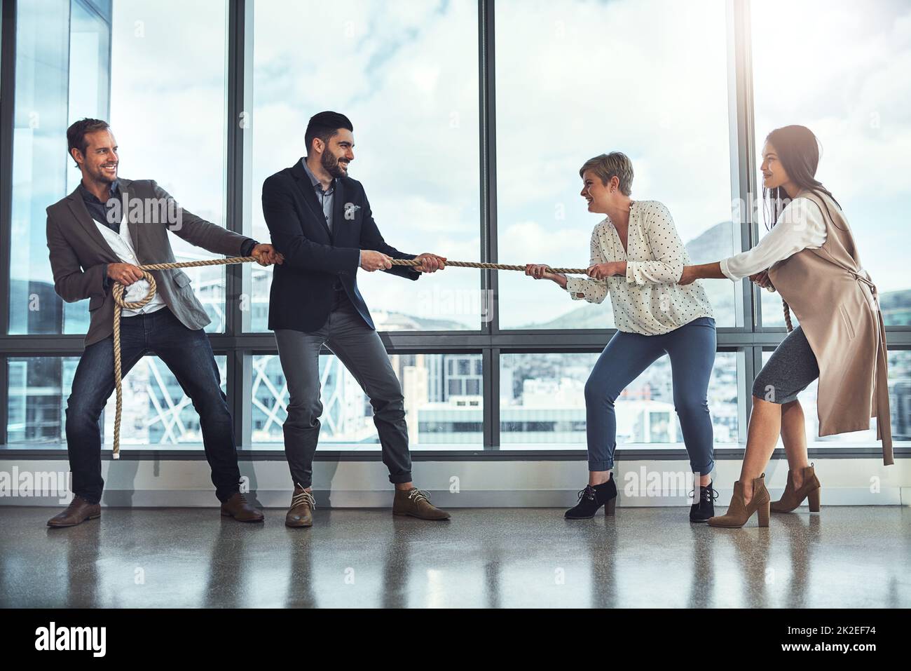 There are many challenges youll have to face in business. Shot of a group of businesspeople pulling on a rope during tug of war in an office. Stock Photo